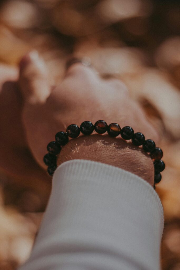 Close-up view of a beaded bracelet on a hand, set against an autumn background.